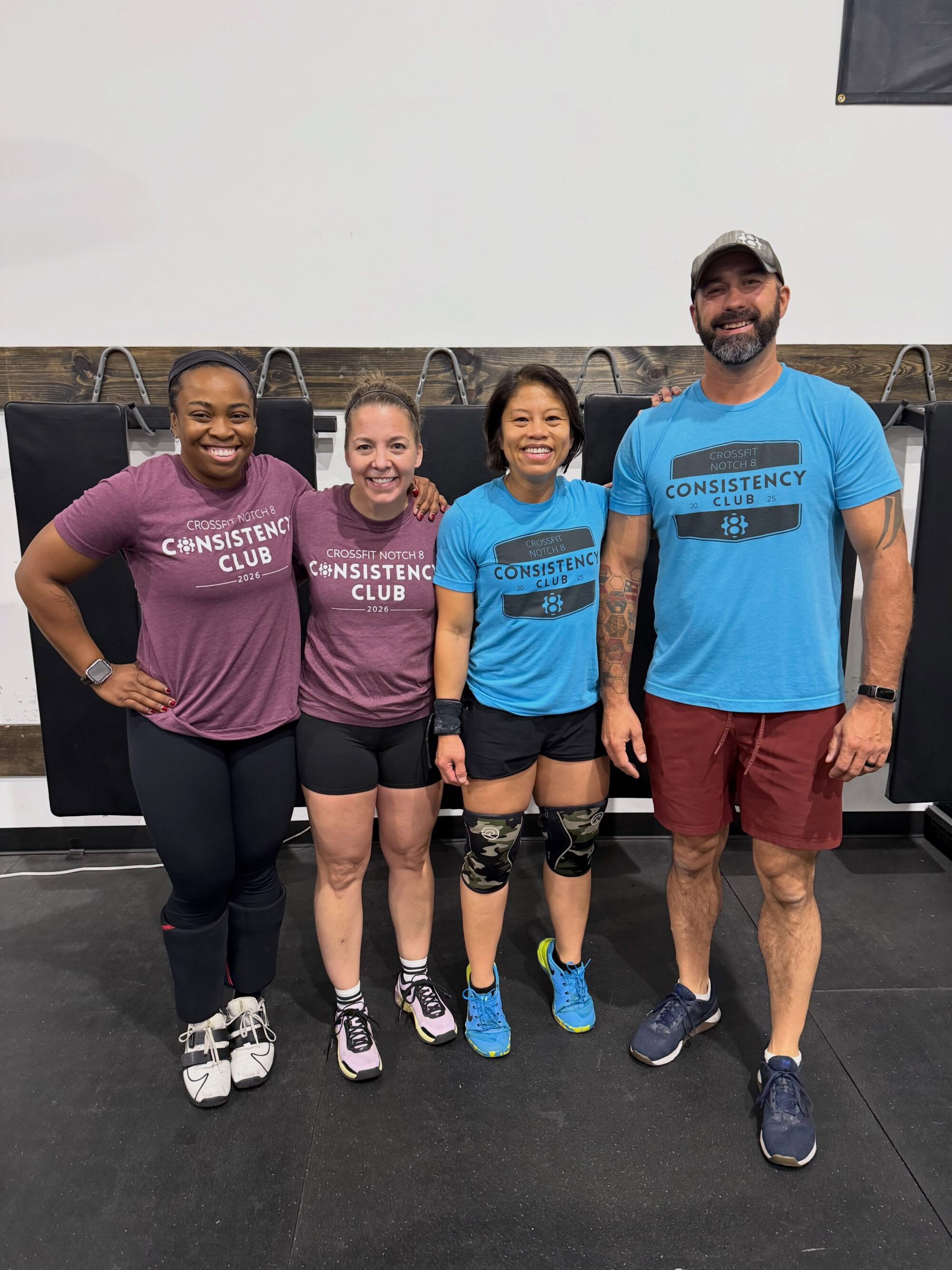 Four CrossFit Notch 8 members wearing matching 2025 and 2026 Consistency Club shirts in the Avon gym